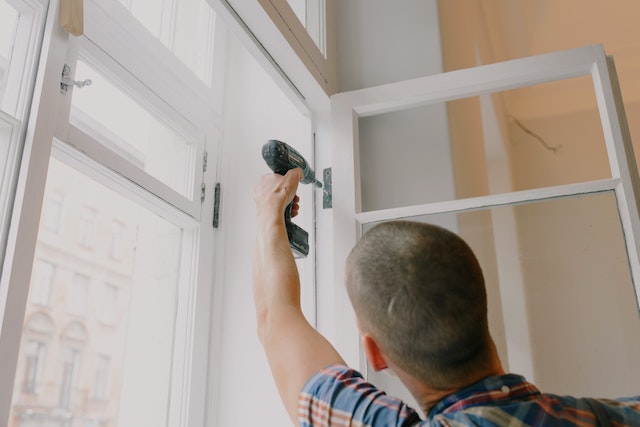 someone fixing a window with a drill